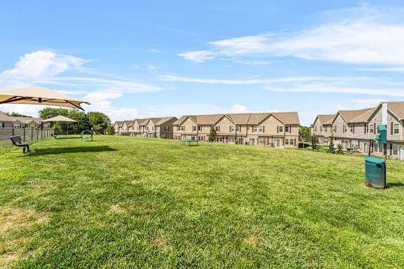 A grassy field with a row of houses in the background.