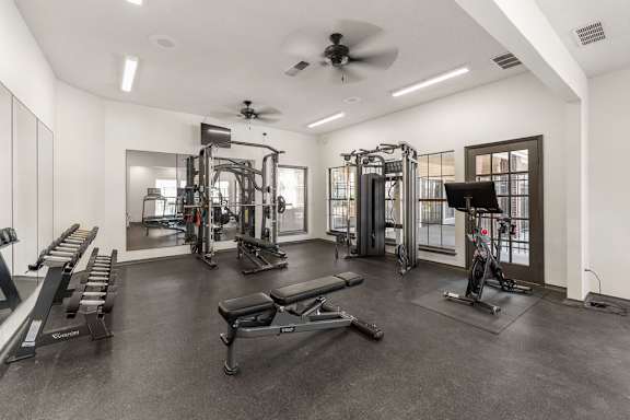 A spacious gym with a variety of equipment including a treadmill, a bench press, and a squat rack.