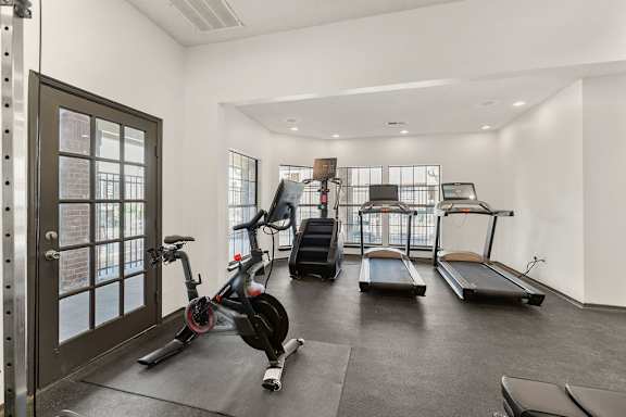 A gym with a treadmill, a stationary bike and a rowing machine.