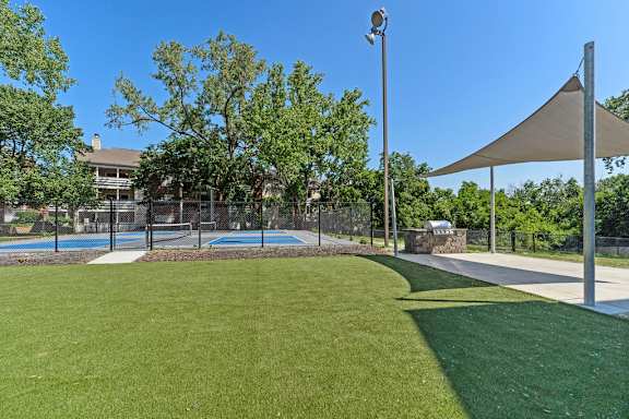 A park with a grassy area, a shaded bench, and a pool.