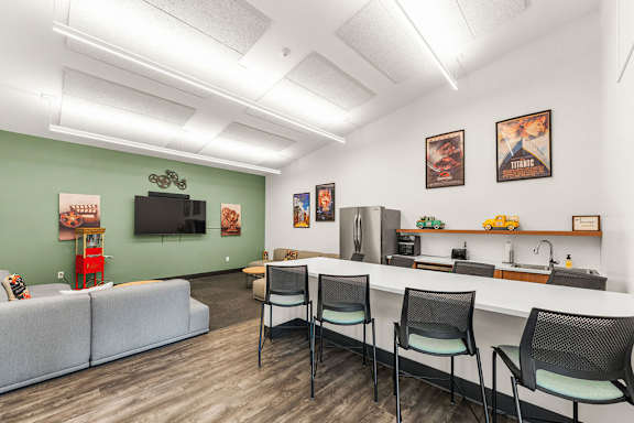 A room with a grey couch, a white counter, and a TV on the wall.