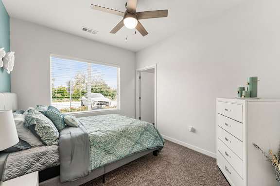 A bedroom with a bed, dresser, and window.
