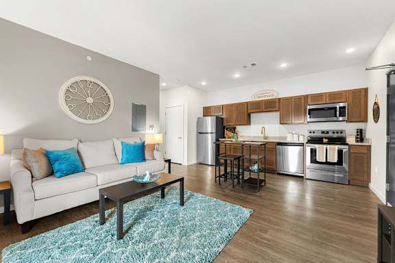 A modern kitchen and living room with a couch, coffee table, and appliances.
