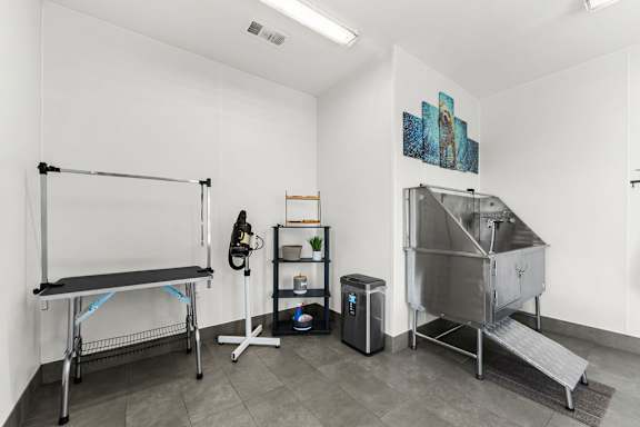 A room with a bench, a shelf, a trash bin, and a stainless steel container.