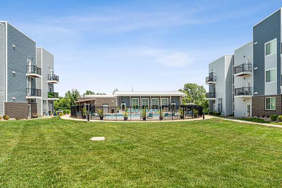 A grassy area in front of apartment buildings with a playground.
