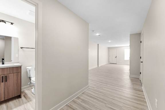A long, empty hallway with wood flooring and white walls.