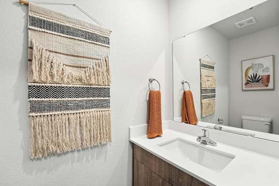 A bathroom with a white sink and a wall hanging.