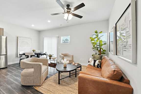 A living room with a brown couch, a coffee table, and a ceiling fan.