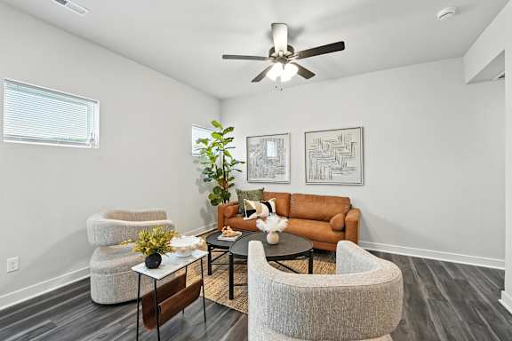 A living room with a brown couch, a white chair, and a plant.