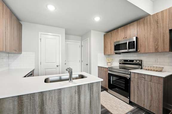 A modern kitchen with a sink, oven, and microwave.