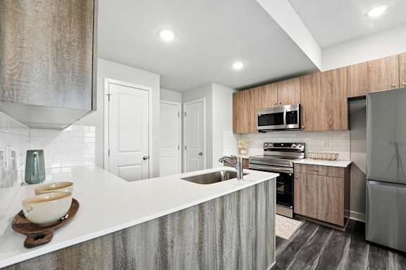 A modern kitchen with a white countertop and stainless steel appliances.