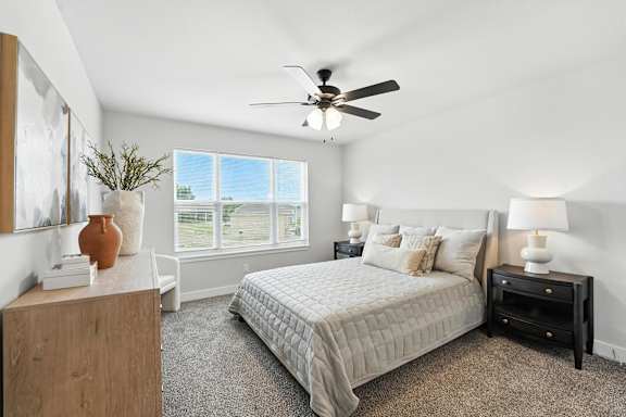A bedroom with a bed, nightstand, and a ceiling fan.
