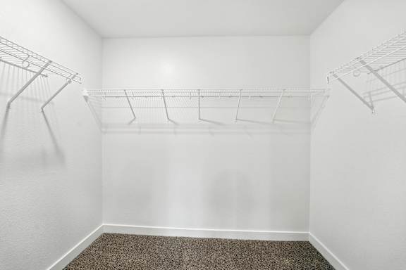 A white closet with a carpeted floor and two wire shelves.