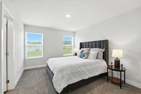 A bedroom with a large bed and a window overlooking a green field.