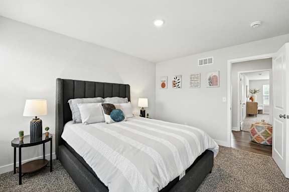 A bedroom with a large bed and a nightstand with a lamp.