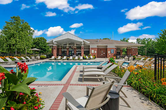 A pool area with chairs and a building in the background.