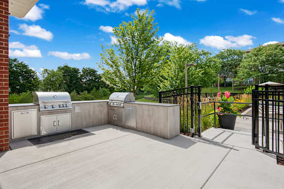 A concrete patio with a black fence and a tree in the background.