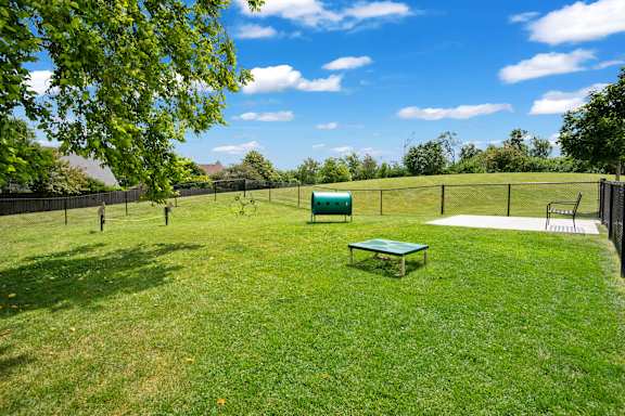 A green lawn with a table and chairs in the middle of it.