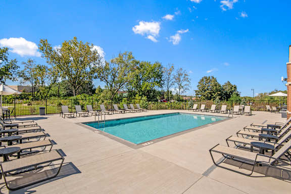 A pool surrounded by lounge chairs on a sunny day.