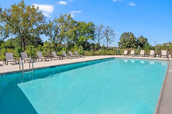 A large swimming pool surrounded by trees and lounge chairs.