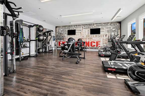 A gym with a variety of equipment including treadmills, weights, and exercise machines.