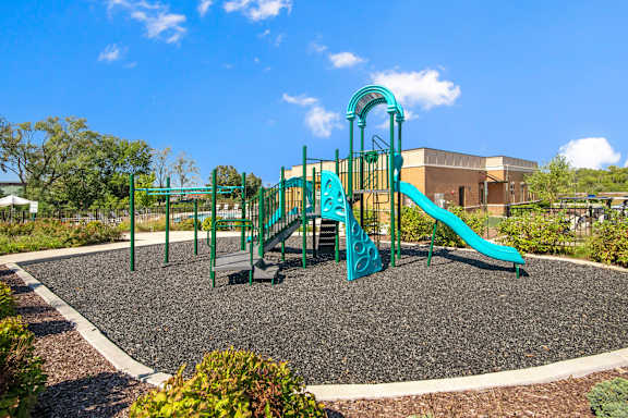 A playground with a green slide and a climbing frame.