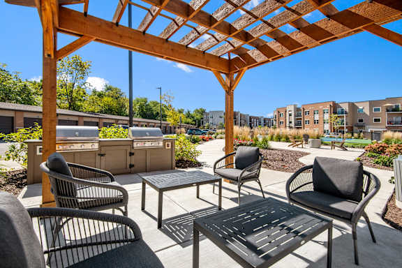 A wooden pergola with a table and chairs in front of a building.