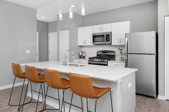 A kitchen with a white countertop and orange chairs.
