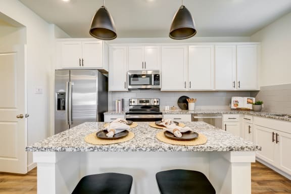 a kitchen with white cabinets and a white island with black stools
