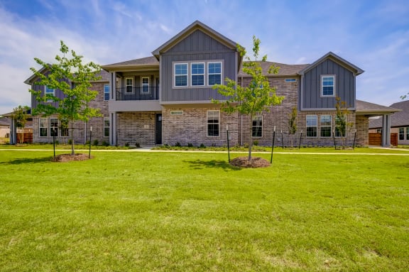 a large lawn in front of a house with trees