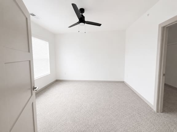 A room with a ceiling fan and carpeted floor.