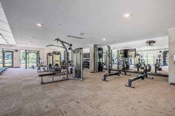 A gym with a variety of equipment including treadmills, weights, and exercise machines.