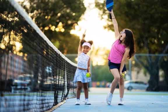 a mother and daughter playing tennis on a tennis court