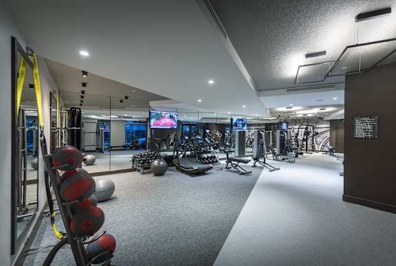 A gym with a variety of equipment including dumbbells, weight machines, and a flat screen TV.