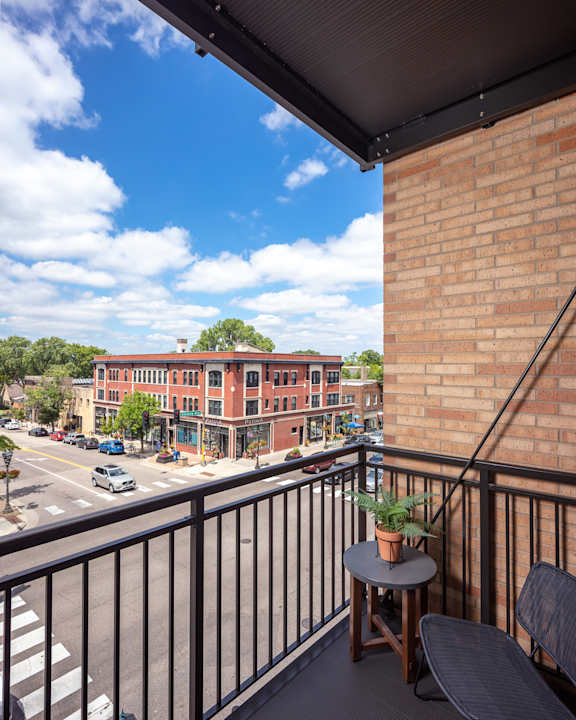 A balcony with a table and chairs overlooking a street.
