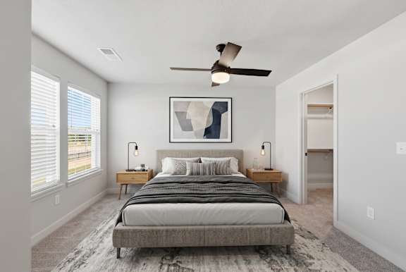 A bedroom with a bed, nightstands, and a ceiling fan.