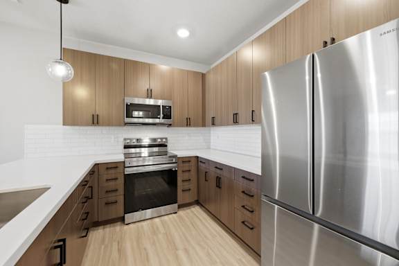 A modern kitchen with a stainless steel refrigerator and wooden cabinets.