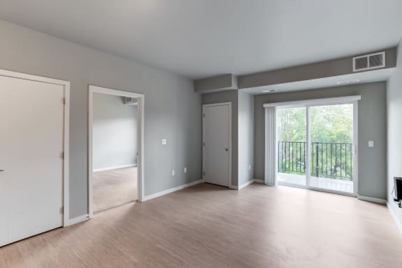 an empty living room with a sliding glass door to a balcony