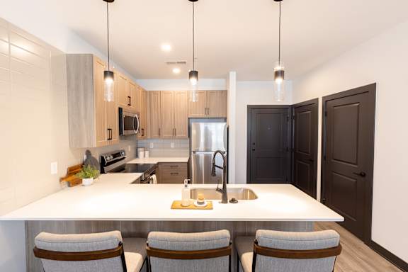 a kitchen with a large white island with a sink and four chairs