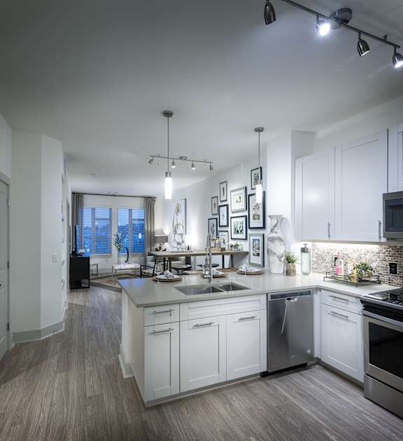 A modern kitchen with white cabinets and a wooden floor.