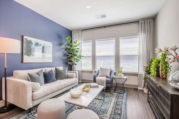 A living room with a white couch, a coffee table, and a painting on the wall.