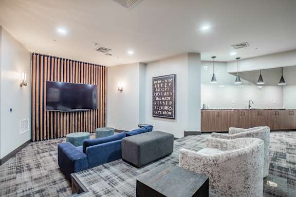A living room with a grey sofa, a black coffee table, and a TV on the wall.