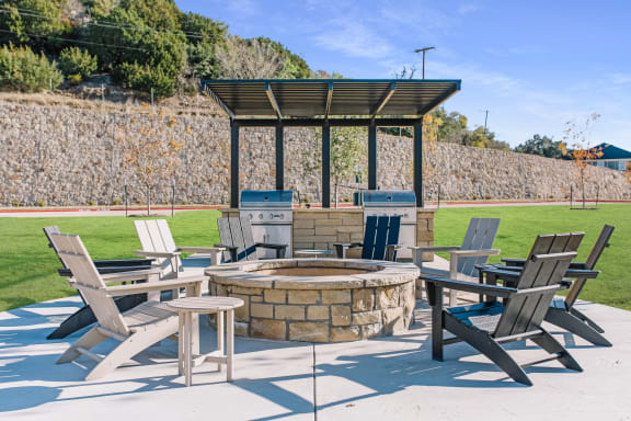 a patio with tables and chairs around a fire pit