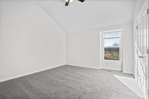 A room with a grey carpet and a window showing a field.