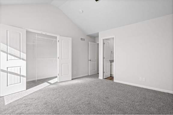 A white room with a grey carpet and three doors.