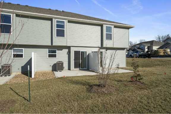 A residential building with a grey siding exterior and a small front yard with a mailbox and a small tree.