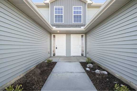 A house with a grey siding and a white door.