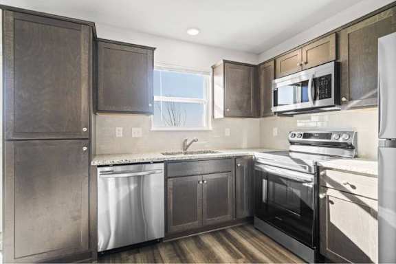 A kitchen with dark wood cabinets and stainless steel appliances.