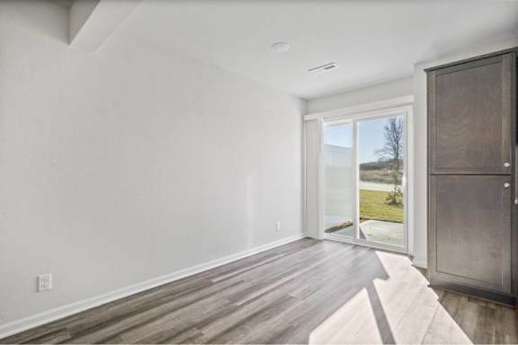 A room with a wooden floor and a sliding glass door leading to a backyard.