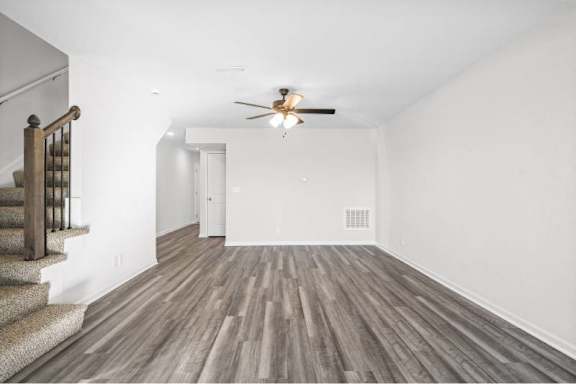 A room with a staircase and a ceiling fan.